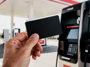 Zakenman houdt zwarte tankpas vast bij modern Nederlands tankstation met rood verlichte betaalterminal.