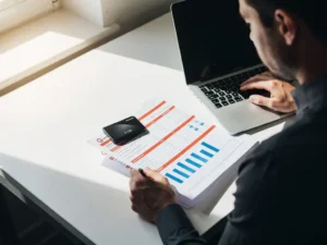 Vlootbeheerder bekijkt brandstofrapportages naast laptop met zwarte brandstofpas op bureau in moderne werkruimte.